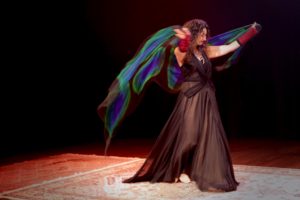 DCA Cultural Trailblazer Sholeh Wolpé is an Iranian-born poet, playwright and librettist. Sholeh dances with a turquoise fabric in a dark room